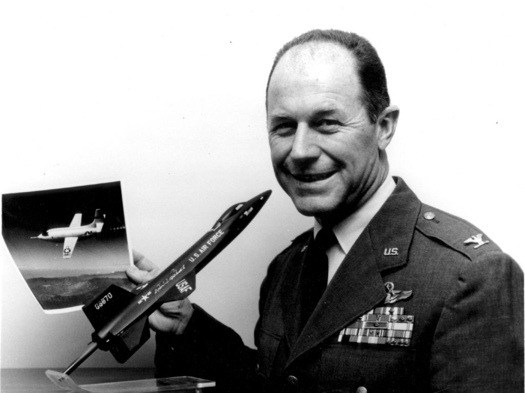 USAF-Col. Charles S. Yeager, Commandant of the USAF Aerospace Research Pilot School at the Air Force Flight Test Center, Edwards AFB, Calif., poses with a model of the North American X-15 high speed, high-altitude research aircraft.  he holds a photograph of the Bell X-1 aircraft in which he became the first man to fly faster than the speed of sound on Oct. 14, 1947.
