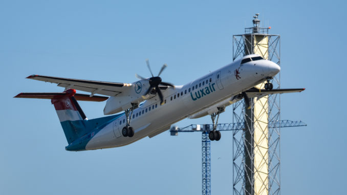 A Dash 8 climbs out from London City Airport past the new digital control tower mast