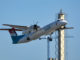 A Dash 8 climbs out from London City Airport past the new digital control tower mast